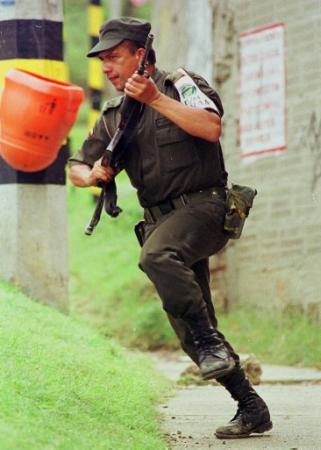 Полицейский офицер бежит, атакуя предположительно городскую милицию левых 
повстанцев Революционных Вооруженных Сил Колумбии, или FARC, в Медельине, 
Колумбия, во вторник, 21 мая 2002 г. Война ворвалась внутрь второго по 
величине города Колумбии во вторник, сразу унеся по крайней мере восемь жертв, 
включая двух детей, погибших среди вооруженных столкновений между 
правительственными отрядами, полицейскими и, предположительно, 
левыми повстанцами. Эти столкновения были лишь звеньями многочисленных 
городских уличных боев в течение 38 лет войны. 
Фото и аннотация: Луис Бенавидес, агентство Ассошиэйтед Пресс. 
