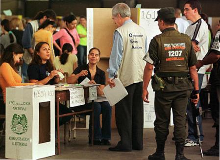 Наблюдатель на выборах от Организации Американских Государств 
Филипп Мак-Лин прекращает разговоры между работниками в ходе выборов 
на избирательном участке в Медельине, Колумбия, в воскресенье, 26 мая 2002. 
Фото и аннотация: Луис Бенавидес, агентство Ассошиэйтед Пресс.
