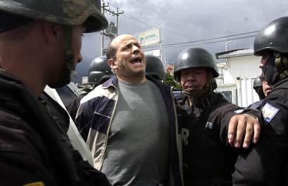 Симон Тринидад, один из семи членов руководящего Национального Секретариата Революционных Вооружённых Сил Колумбии, выкрикивает лозунги, будучи сопровождаемым эквадорскими полицейскими по прибытии на авиабазу в Кито, в субботу, 3 января 2004 г. Эквадорские власти арестовали самого высокопоставленного члена партизанской армии, из когда-либо захваченных за четыре десятилетия партизанской войны, что является самой большой победой в кампании бескомпромиссного колумбийского Президента Альваро Урибе, направленной на сокпушение левого повстанчества. Фото и аннотация: Долорес Очоа, агентство Ассошиэйтед Пресс, суббота 03 января 2004 г., 15 ч. 23 мин. всемирного времени