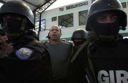 Симон Тринидад, один из семи членов руководящего Национального Секретариата Революционных Вооружённых Сил Колумбии, (в центре) сопровождается в наручниках эквадорской полицией по прибытии на авиабазу в Кито, в субботу, 3 января 2004 г. Эквадорские власти арестовали самого высокопоставленного члена партизанской армии, из когда-либо захваченных за четыре десятилетия партизанской войны, что является самой большой победой в кампании бескомпромиссного колумбийского Президента Альваро Урибе, направленной на сокпушение левого повстанчества. Фото и аннотация: Долорес Очоа, агентство Ассошиэйтед Пресс, суббота 03 января 2004 г., 15 ч. 44 мин. всемирного времени