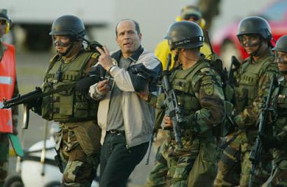 Симон Тринидад, член руководящего Национального Секретариата Революционных Вооружённых Сил Колумбии, или FARC, взрывается символом победы, будучи экскортируемым специальными силами на военной базе в Боготе, Колумбия, в субботу, 3 января 2004. Эквадорские власти арестовали самого высокопоставленного члена партизанской армии, из когда-либо захваченных за четыре десятилетия партизанской войны, что является самой большой победой в кампании бескомпромиссного колумбийского Президента Альваро Урибе, направленной на сокпушение левого повстанчества. Фото и аннотация: Хавьер Галеано, агентство Ассошиэйтед Пресс, суббота 03 января 2004 г., 18 ч. 25 мин. всемирного времени