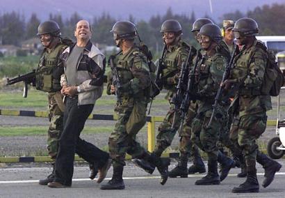 Симон Тринидад, один из семи членов руководящего Национального Секретариата Революционных Вооружённых Сил Колумбии, выкрикивает лозунги, будучи сопровождаемым срециальными силами на военной базе в Боготе, Колумбия, в субботу, 03 января 2004 г. Эквадорские власти арестовали самого высокопоставленного члена партизанской армии, из когда-либо захваченных за четыре десятилетия партизанской войны, что является самой большой победой в кампании бескомпромиссного колумбийского Президента Альваро Урибе, направленной на сокпушение левого повстанчества. Фото и аннотация: Фернандо Вергара, агентство Ассошиэйтед Пресс, суббота 03 января 2004 г., 18 ч. 37 мин. всемирного времени.