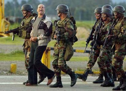 Колумбийский повстанческий команданте Симон Тринидад сопровождается солдатами по прибытию на военный аэропорт ``Катам'' города Боготы 3 января 2004 г. Команданте высокого ранга марксистской повстанческой армии Колумбии, FARC, был арестован 2 января в больнице в соседнем Эквадоре, и является самым высокопоставленнsv членом партизанской армии, из когда-либо захваченных за четыре десятилетия партизанской войны. Фото и аннотация: Элиана Апонте, агентство Рейтер, понедельник 05 января 2004 г., 08 ч. 07 мин. всемирного времени