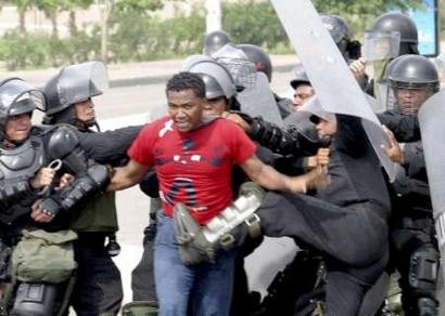 Колумбийская антитеррористическая полиция избивает демонстранта в ходе акции протеста в Картахене 18 мая 2004 г. Тысячи протестующих вышли на улицы по всей Колумбии во вторник, поскольку разорванная войной нация принимала гостей, занимающихся переговорами по установлению в Андском регионе зоны вободной торговли с Соединенными Штатами. Колумбия, Перу и Эквадор - с общим населением в 80 миллионов потребителей, главным образом бедных, начнут переговоры с самой большой в мире экономикой с инаугурационной церемонии этим вечером в усаженом пальмами портовом городе Картахена. Фото и аннотация: Элиана Апонте, агентство Рейтер, вторник 18 мая, 17 ч. 42 мин. всемирного времени.