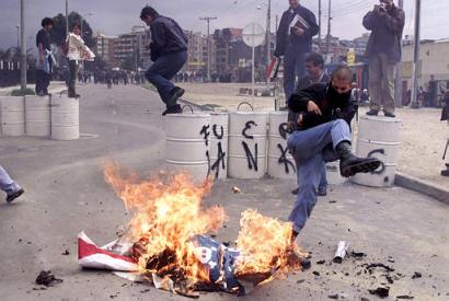 Студенты жгут макет американского флага в ходе протеста против руководимого США вторжения в Ирак перед американским посольством в Боготе, Колумбия, в четверг, 27 марта 2003. Приблизительно 1 500 протестующих, главным образом студенты университета, пришли к зданию посольства, где полиция применила слезоточивый газ и резиновые пули после того, как демонстраторы зажгли шины, бросили небольшие взрывпакеты в полицию и подожгли американский флаг. 
Фото и аннотация: Фернандо Вергара, агентство Ассошиэйтед Пресс, четверг 27 марта 2003 г; 15 ч. 42 мин. всемирного времени