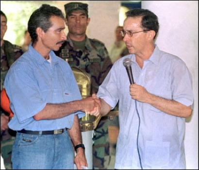 Колумбийский Президент Альваро Урибе, справа, обменивается рукопожатиями с Фиделем Ромеро, по прозвищу Рафаэль, называющим себя командующим 46-ого Фронта Революционных Вооруженных Сил Колумбии (FARC), в ходе пресс-конференции в Картахене, приблизительно в 405 милях к северу от Боготы, Колумбия, в понедельник, 28 апреля 2003. Как заявил в понедельник Урибе, предводительствовавший отрядами FARC в северном департаменте Сантандер Ромеро, сдался в пятницу должностным лицам Колумбии. Фото и аннотация: Стрингер, агетство Рейтер и Агентство Франс Пресс (архив), понедельник 28 апреля 2003 г., 14 ч. 44 мин. всемирного времени