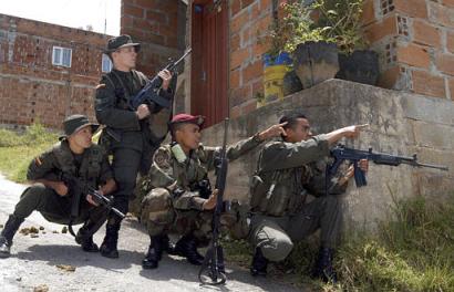Des détachements colombiens se cachent derrière des couverts, en patrouillant les rues de la Granada, qui est au nord-ouest de la Colombie, au cours de lattaque des insurgés après larrivée à Granada du président de la Colombie Alvaro Uribe, dimanche, le 17 août 2003. Une photo et une annotation: Cesar Carrion, lagence AP -Photo avec la référence aux agences HO et CNN, dimanche, le 17 août 2003, 20 h. 25 min. du temps mondial