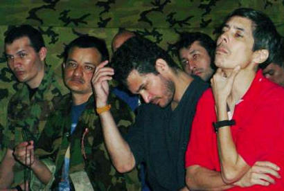 Удерживаемые в плену Революционными Вооруженными Силами Колумбии (FARC-EP) и бывшие пять лет назад 
солдатами Эрасмо Ромеро (слева), Либардо Фореро (второй слева) и Карлос Дуке (второй справа), сфотографированы в 
колумбийских джунглях 26 июля 2003 г. На заднем плане справа - Алан Хара, бывший колумбийский провинциальный 
губернатор, также взятый в плен повстанцами во время его передвижения на автомобиле Организации Объединенных 
Наций в центральной Колумбии два года назад. Фото и аннотация Энрике Ботеро, агентство Рейтер, опубликованы 
во вторник, 26 августа 2003 г., 16 ч. 05 мин. всемирного времени