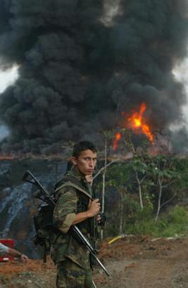 Un soldat monte la garde  devant un puits à pétrole, incendié par des insurgés dans la région de village Puerto Asis, dans la jungle du département sud Putumayo, mercredi, le 13 août 2003. Cinq puits ont été explosés dans la région le 12 juillet par des Forces Armées Révolutionnaires Colombiennes, connues comme  (FARC-EP). Un détachement américain, qui avait aidé à éteindre les incendies pareils sur les puits à pétrole dans la région du golfe Persique, est déjà arrivé en Colombie pour lutter avec les incendies et contrôler un dégagement du pétrole et du gaz. Une photo et une annotation: Javier Galeano, lagence AP - Photo, jeudi, le 14 août, 11 h. 06 min. du temps mondial