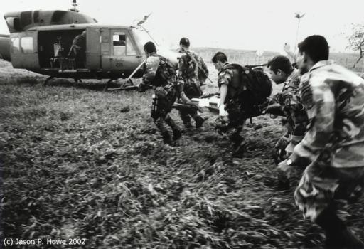 Борясь против воздушных потоков, создаваемых вертолетными винтами, 
солдаты бегут вперед, чтобы загрузить своего раненного товарища в вертолет. 
Фото и аннотация: Джейсон П.Хоуэ, 2002 г.
