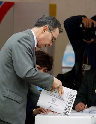 Президент Колумбии Альваро Урибе кидает свой избирательный бюллетень перед голосованием на референдуме по его предложениям, напрвленным  на снижение расходов правительства, уменьшение размера Конгресса и борьбу с политической коррупцией в Боготе, в субботу, 25 октября 2003 г. Фото и анотация: Хавьер Галеано, агентство Ассошиэйтед Пресс, суббота 25 октября 2003 г., 10 ч. 27 мин. всемирного времени.