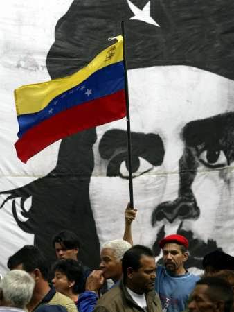 Сторонники венесуэльского Президента Уго Чавеса размахивают национальным флагом перед плакатом с изображением аргентинского героя Эрнесто ''Че'' Гевары в ходе акции у стен Центрального Банка в Каракасе 7 января 2004 г. Чавес потребовал на прошлой неделе выделения в течение трех недель одного миллиарда долларов инвалютных запасов Центрального Банка для правительственных сельскохозяйственных проектов, под угрозой, в противном случае, применения санкций Верховного Суда. Фото и анотация: Хорхе Сильва, агентство Рейтер, среда, 7 января 2003 г, 14 ч. 04 мин. всемирного времени