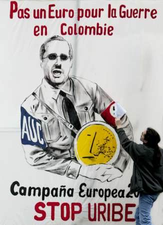 Человек пытается скрывать нацистскую свастику на левой руке колумбийского Президента Альваро Урибе Велеса, изображенного на гигантском постере с текстом ``Ни евро для войны в Колумбии'', в течение протеста около здания европейского Совета в Брюсселе, 9 февраля 2004. Приблизительно 100 человек протестовали против посещения Урибе ряда европейских иститутов. Фото и аннотация: Ив Эрман, агентство Рейтер, понедельник, 9 февраля 2003 г., 07 ч. 38 мин. всемирного времени