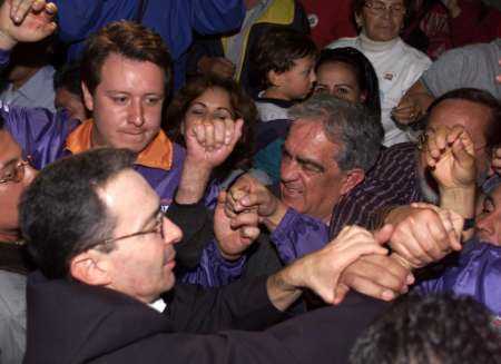 Колумбийский кандидат в президенты Альваро Урибе приветствует сторонников на политической встрече в Боготе, 19 мая 2002 г. При повышенных мерах безопасности кандидаты, выдвинутые колумбийское президентсво для выборов 26 мая, закончили свою кампанию в воскресенье, при этом опросы продемонстрировали подавляющее превосходсьво Альваро Урибе, кандидата-антиповстанца, которому электоральное большинства может позволить избежать последнего тура голосования в июне. Фото и аннотация: Даниэль Муньос, агентство Рейтер,  19 мая 2002 г. 